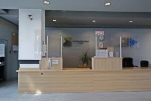 Na zdjęciu widzimy biuro podawcze Zarządu Dróg Wojewódzkich w Lublinie. Blat znajduje się na wysokości 95 centymetrów i umożliwia obsługę osób poruszających się na wózkach. Biuro podawcze czyli blat i półki wykonane są z jasnego drewna.